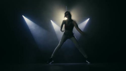 Woman Dancing Under Spotlights in Dark Studio
