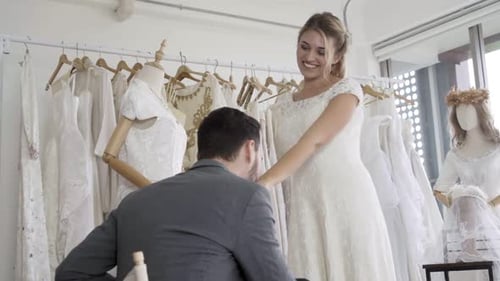 Woman Wearing Wedding Gown Holds Hands With Man