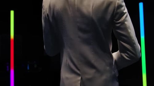 Saxophone Player in a White Suit Performing Against the Backdrop of Neon Lamps in a Dark Studio