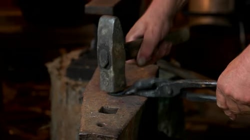 Hands Shaping Metal on Anvil with Hammer