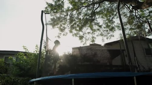 Child Jumps on Trampoline in Backyard