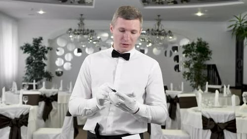 Waiter in a White Shirt and Bowtie Writing Down an Order in a Cafe