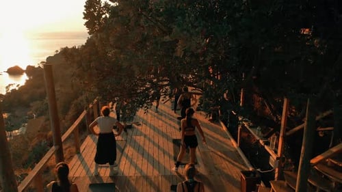 Adults Practicing Yoga on Coastal Platform at Sunset
