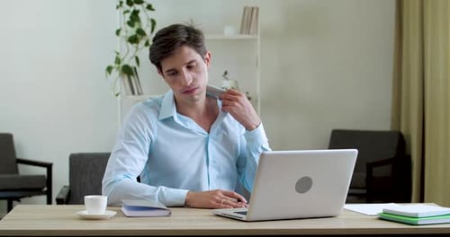Man Using Laptop at Desk Fanning Himself