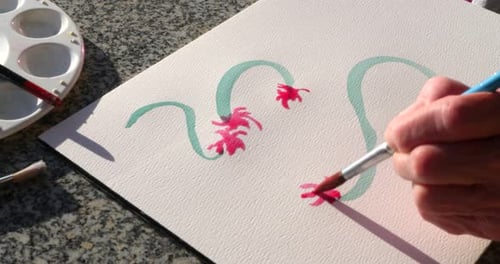 An elderly woman artist painting a colorful floral artwork with watercolor to relax and destress.