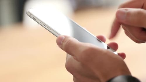 Hands Swiping on Smartphone in Office Setting