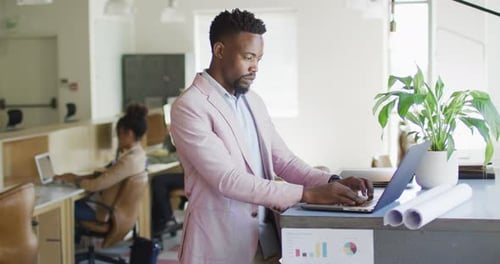 African american businessman using laptop with colleagues in creative office