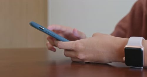 Woman Using Mobile Phone at Table Indoors