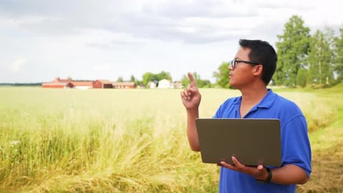 Asiatischer Mann arbeitet auf einer Farm am Laptop