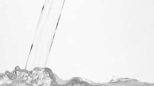 Trinkwasser in Glas über Weiß gießen