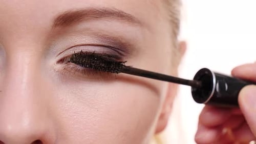 Woman Applying Mascara to Eyelashes in Close-Up