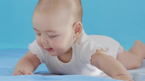 Adorable Baby Lying on Stomach on Blue Surface