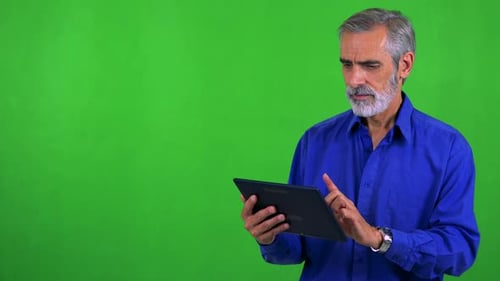 Old Senior Man Works on Tablet - Green Screen - Studio