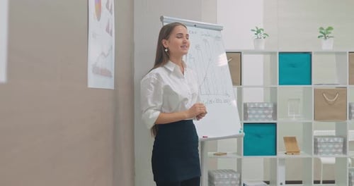 Young Beautiful Woman Talks About the Company's Income Shows on the Graph