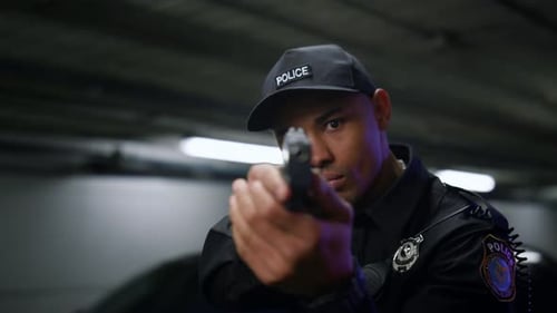 Police Officer Points Gun at Camera at Night