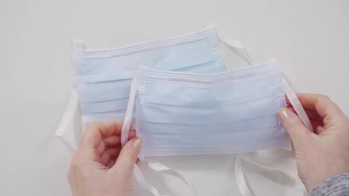 Hands Place Blue Surgical Masks on White Surface