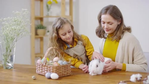 Mother and Daughter Petting White Rabbit Indoors