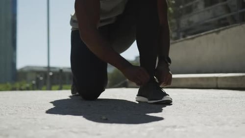 Man Tying Shoelaces and Lunging in the City