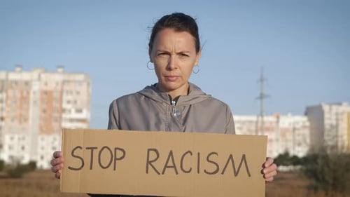 Woman Holds Anti-Racism Sign in Urban Environment