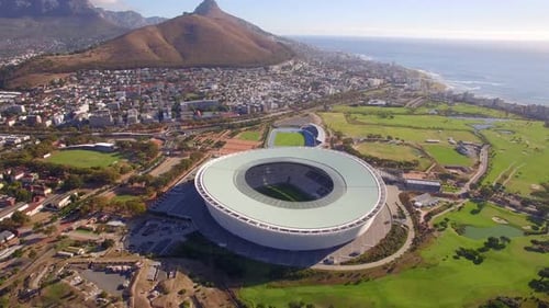 Aerial travel drone view of Cape Town, South Africa with Table Mountain and stadium.