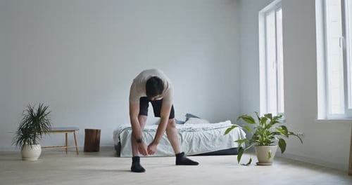 Man Stretching Legs in Minimalist Bedroom