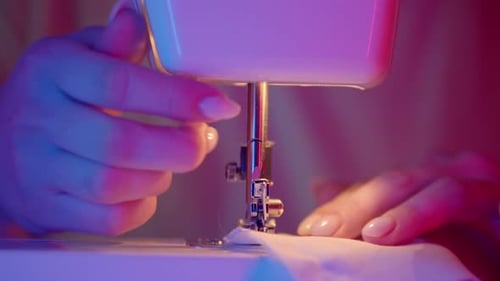Woman Sews White Fabric on Sewing Machine Close Up