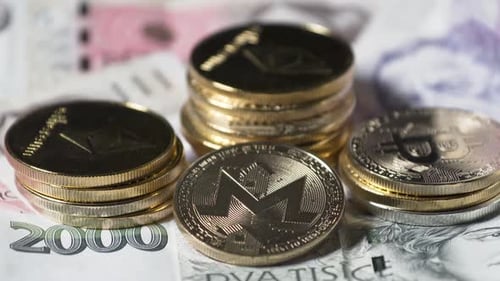 Monero y otras monedas de criptomonedas apiladas en billetes de la corona checa.