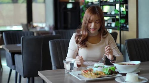 young woman eating with food in restaurant
