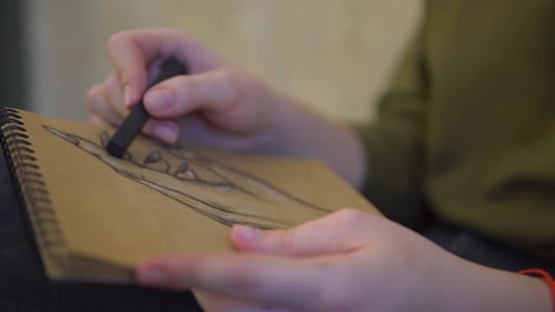 Artiar zeichnet eine Hand im Skizzenbuch von Black Coal Close Up Woman