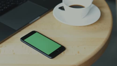 Laptop, Coffee, and Green Screen Phone on Table