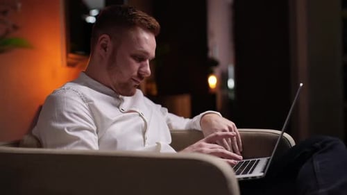 Young Adult Typing on Laptop in Chair