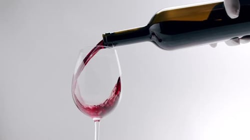 Pouring Red Wine into Glass on Grey Background