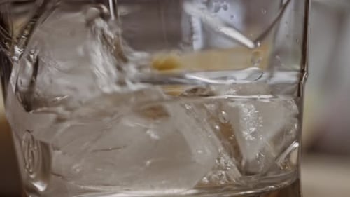 Clear Drink Poured Over Ice Cubes in Glass