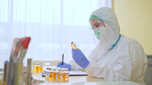 Medical Professional Examines Vials in Protective Suit