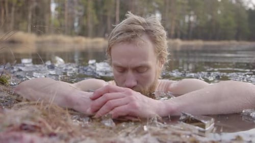 ZOOM AVANT - Un baigneur de glace se concentre sur la respiration consciente alors qu'il est assis dans un lac gelé