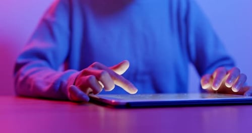 Hands Using Tablet in Blue and Pink Light