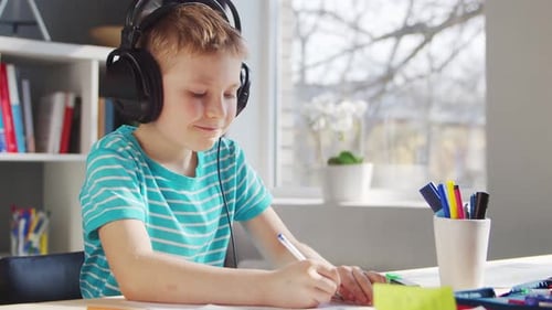 Child Wearing Headphones Drawing at a Desk