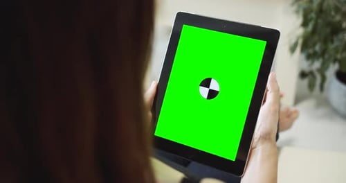 Woman Using Tablet With Green Screen Indoors