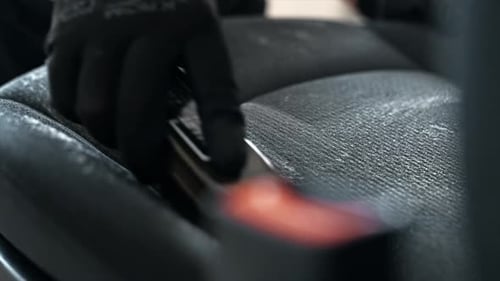 Working cleaner at car wash. Cleaning a seat using a brush and chemical solution. Slow motion