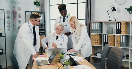 Medical Team Collaborating in Office Over Laptop