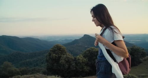 Happy Inspired Young Adult Woman Walk on Top of Mountain at Sunset with Backpack