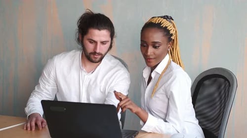 Two Colleagues Collaborate at a Laptop in Office