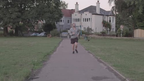Young Athletic Man Goes For A Run In The Park, Runs Towards Camera In Slow Motion - Ungraded