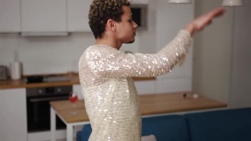 Um homem de vestido se admira dançando sensualmente na cozinha