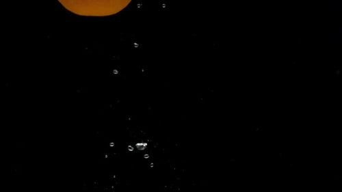 Slow Motion One Orange Falling Into Transparent Water on Black Background