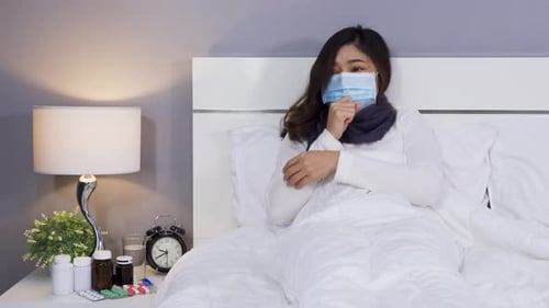 Young Woman Sick in Bed with Surgical Mask