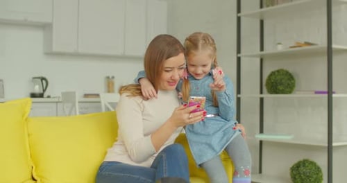 Woman and Child Use Phone Together Indoors
