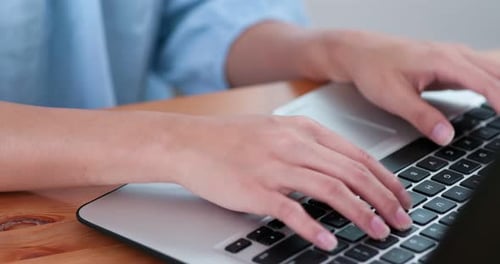 Hands Typing on Laptop Computer Keyboard on Desk