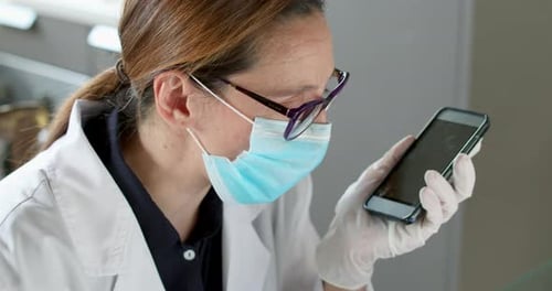 Woman in Lab Coat Using Smartphone