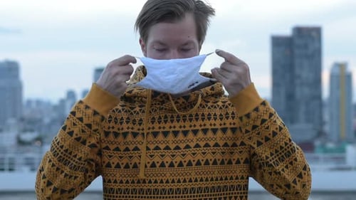 Face of Young Man Wearing Mask for Protection From Corona Virus Outbreak Against View of the City